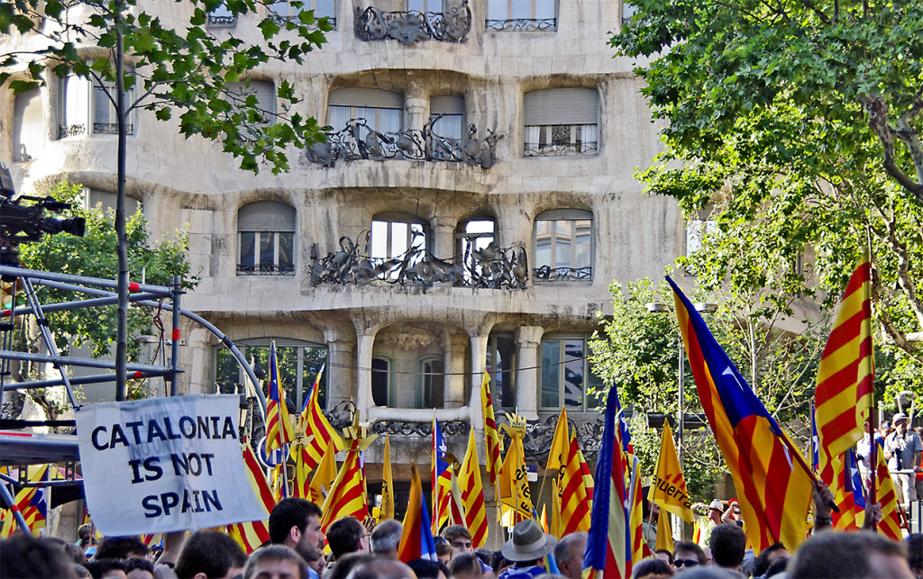 “Catalonia Is Not Spain.” Hundreds of Catalans wearing the traditional colors of the Catalan flag campaign for their independence in front of one of the iconic Gaudí buildings of Barcelona. 2010. (SBA73/Flickr Creative Commons).