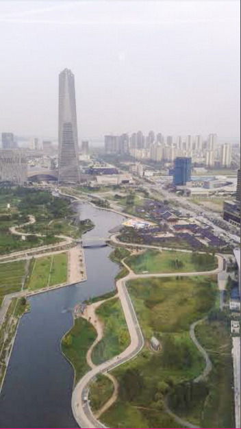 A picture of Central Park, the North East Asian Trade Tower and the surrounding buildings. The canal is composed of salt water from the ocean in order to be sustainable. August 17, 2015. (Personal image).