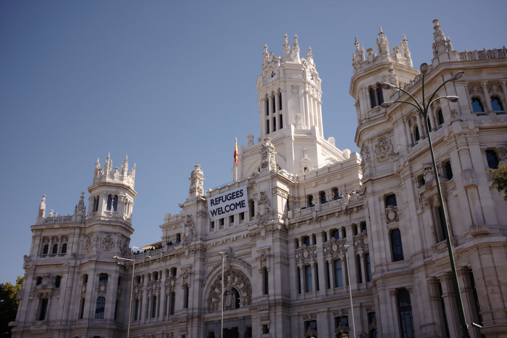 The “Refugees Welcome” sign hangs from the Madrid City Hall to express solidarity with the millions of refugees leaving their country of origin in hopes of finding a home in Western Europe. Unfortunately, Spain has not been truly accepting of refugees and more specifically, of Muslim refugees and descendents. (Nicolas Vigier, Flickr)